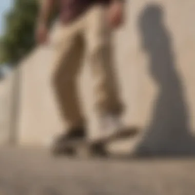 A casual outdoor setting with a skateboard resting against a wall next to a pair of beige corduroy pants.