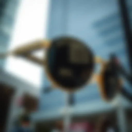 Close-up view of black round sunglasses with gold frame reflecting urban scenery